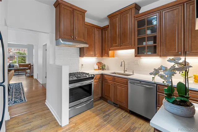 a kitchen with stainless steel appliances granite countertop a stove a sink dishwasher and a refrigerator with wooden floor