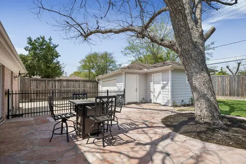 a patio with table and chairs and potted plants