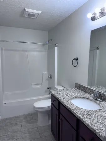 a bathroom with a granite countertop sink a toilet and shower