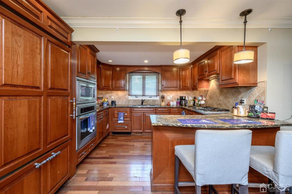 240 Lloyd Road Aberdeen, NJ 07747 - Photo 6 of 29 a kitchen with stainless steel appliances granite countertop a refrigerator a sink dishwasher a stove and a dining table with wooden floor