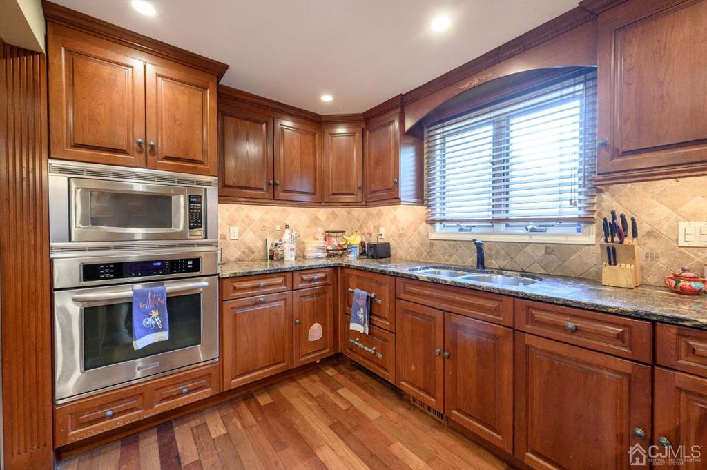 240 Lloyd Road Aberdeen, NJ 07747 - Photo 9 of 29 a kitchen with granite countertop wooden cabinets stainless steel appliances and a window
