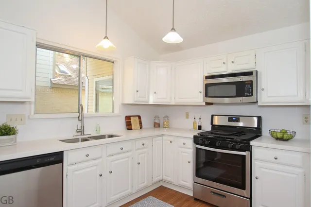 a kitchen with white cabinets stainless steel appliances and sink