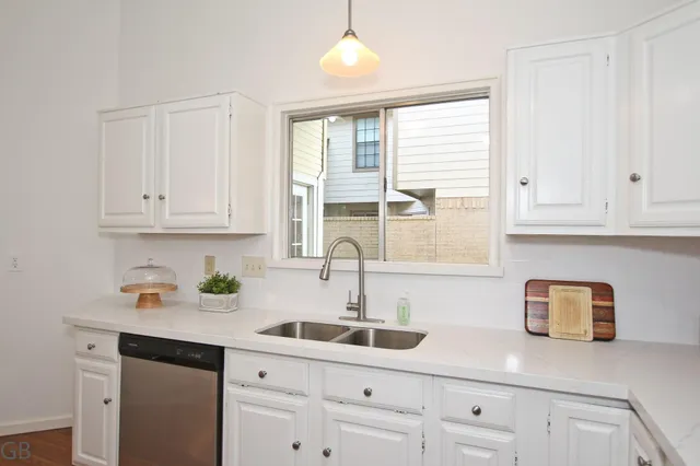 a kitchen with white cabinets and a window