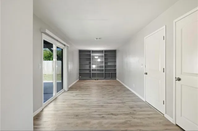 a view of a hallway with wooden floor and windows