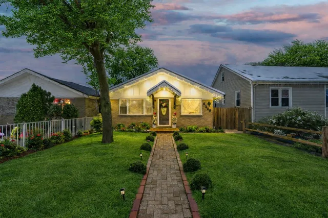 a view of a house with a small yard plants and large trees
