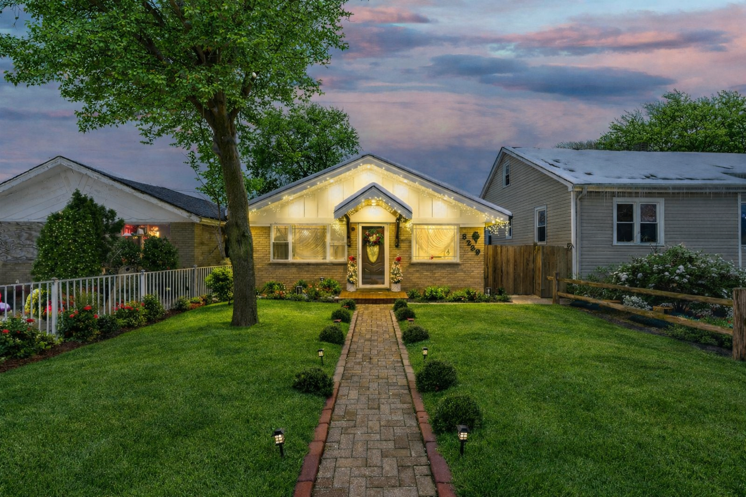a view of a house with a small yard plants and large trees