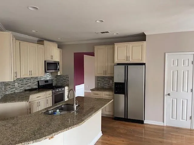 a kitchen with granite countertop white cabinets and stainless steel appliances