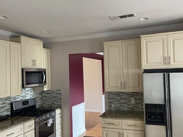 a kitchen with stainless steel appliances kitchen island granite countertop a refrigerator and a stove top oven