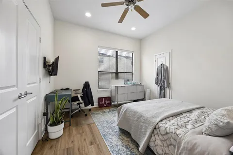 a bedroom with a bed a desk and chair with the potted plants