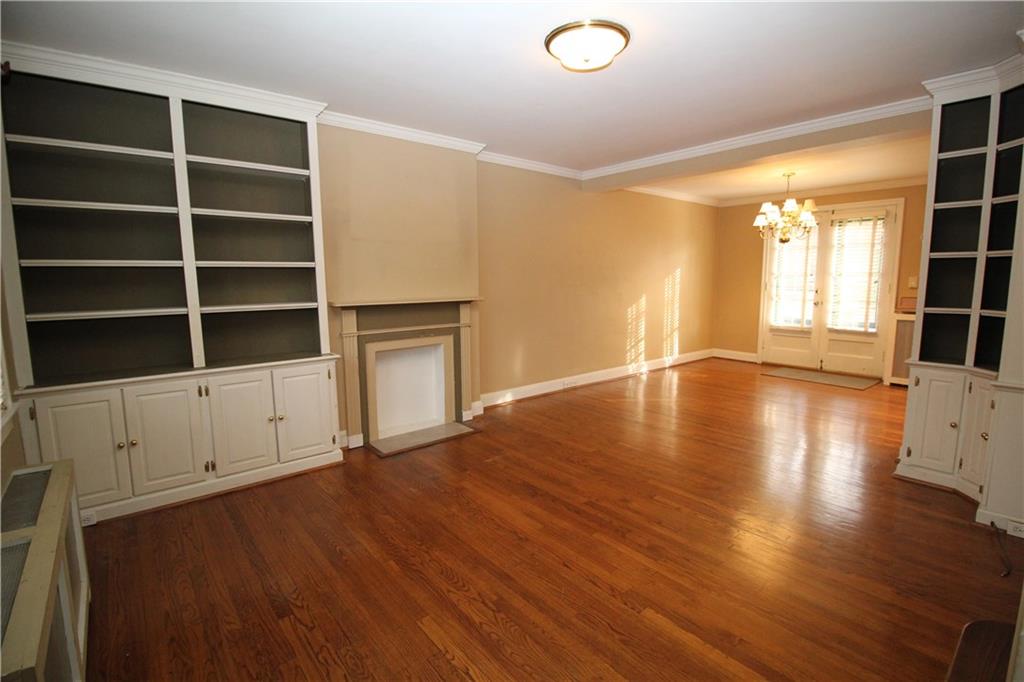 437 Olympia Road Pittsburgh, PA 15211 - Photo 3 of 23 Living room with custom built-in cabinets and decorative fireplace showing open floor plan, wood floors that flow throughout the home, and french doors leading to rear garden.