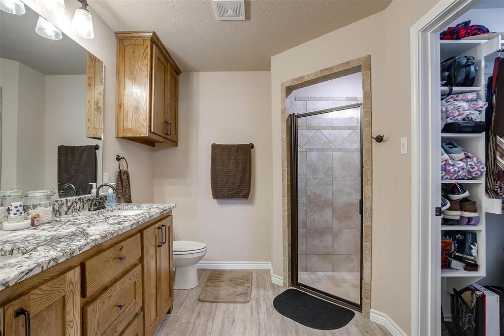 2140 Brown Loop Poolville, TX 76487 - Photo 17 of 38 a bathroom with a granite countertop sink a toilet a mirror and shower