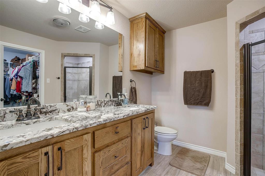 2140 Brown Loop Poolville, TX 76487 - Photo 18 of 38 a bathroom with a granite countertop sink a toilet and a mirror