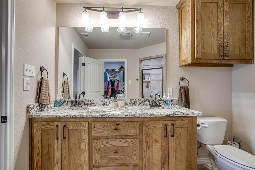 2140 Brown Loop Poolville, TX 76487 - Photo 25 of 38 a bathroom with a granite countertop sink a toilet and a mirror