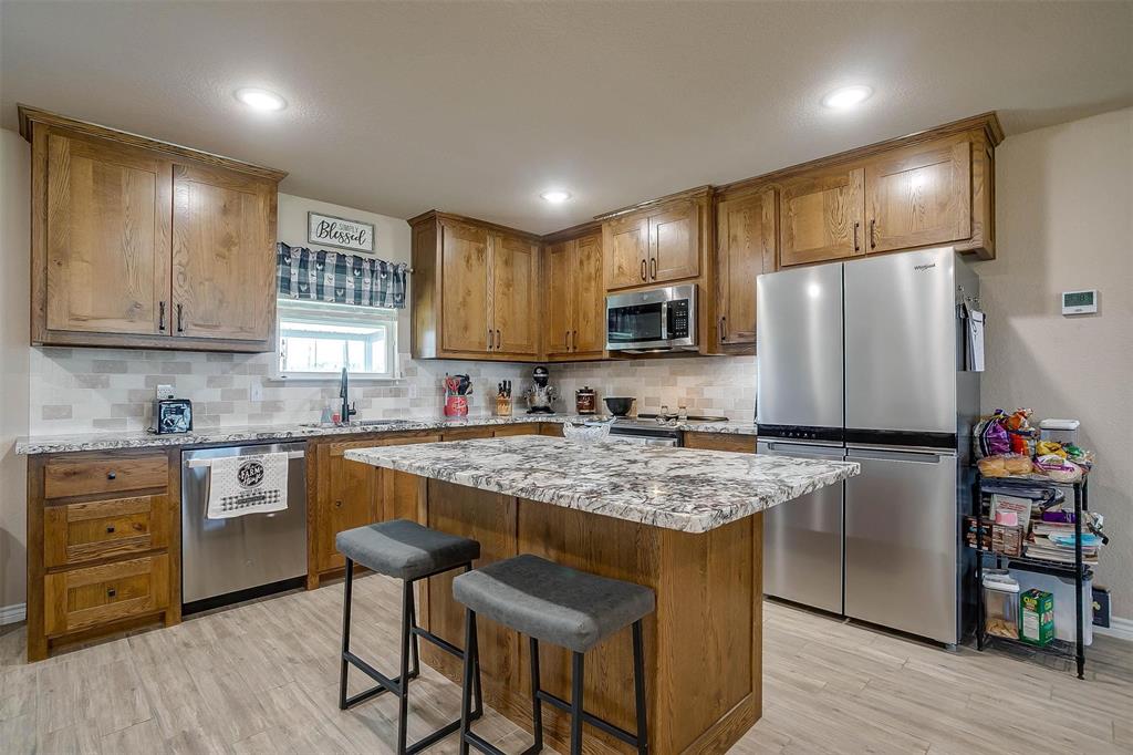 2140 Brown Loop Poolville, TX 76487 - Photo 6 of 38 a kitchen with kitchen island granite countertop wooden cabinets and refrigerator
