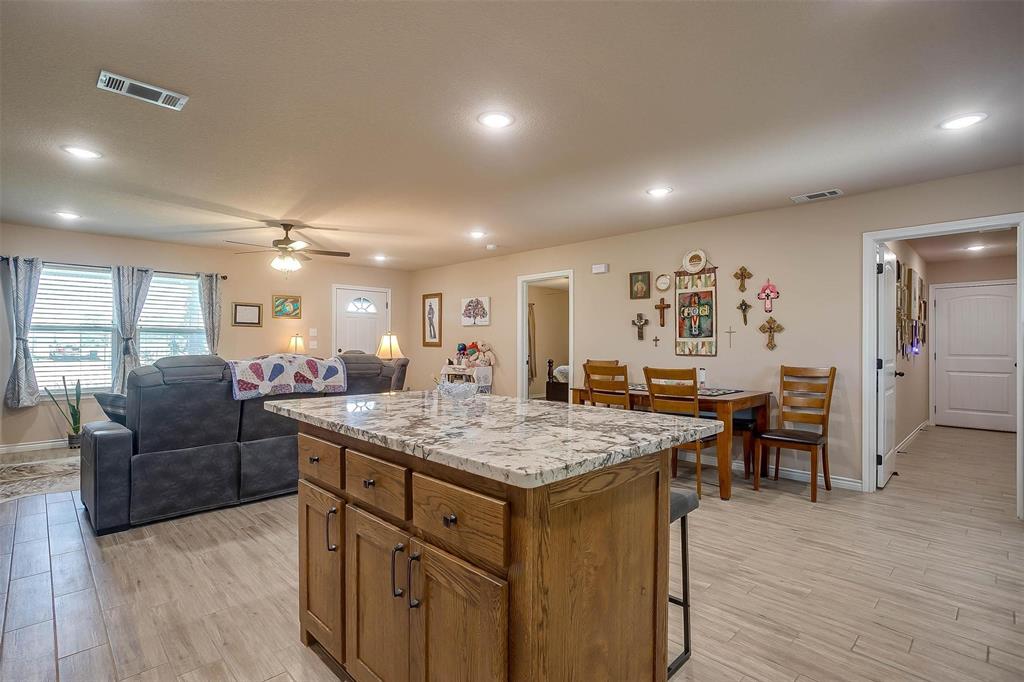 2140 Brown Loop Poolville, TX 76487 - Photo 8 of 38 a dining hall with stainless steel appliances granite countertop a sink dishwasher and a dining table with wooden floor