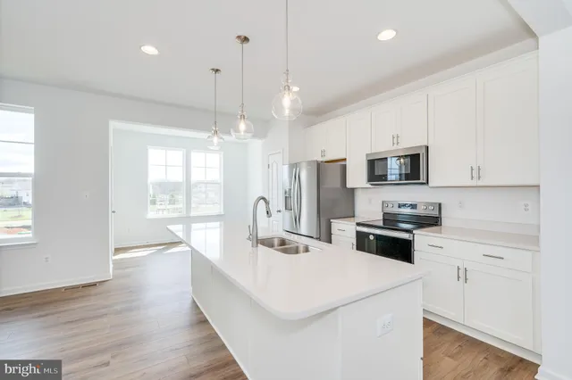 a kitchen with stainless steel appliances a sink a stove a refrigerator cabinets and a window