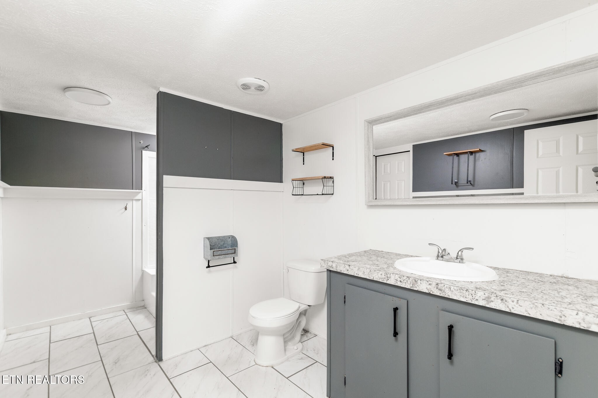 297 Wells Road Powell, TN 37849 - Photo 10 of 15 a bathroom with a granite countertop sink a mirror and a toilet