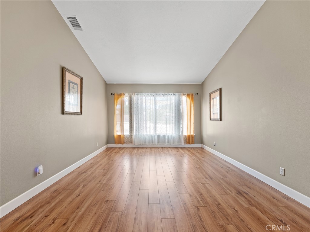 12949 Choco Road Apple Valley, CA 92308 - Photo 8 of 48 a view of an empty room with wooden floor and a window