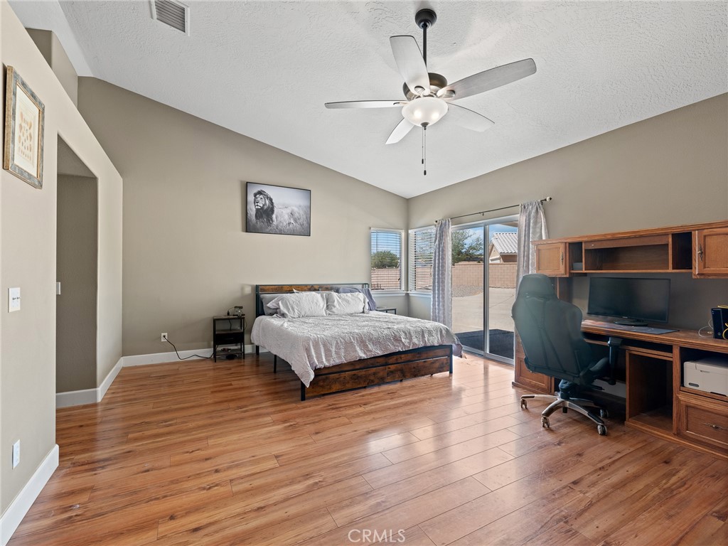 12949 Choco Road Apple Valley, CA 92308 - Photo 10 of 48 a spacious bedroom with a bed and a chandelier