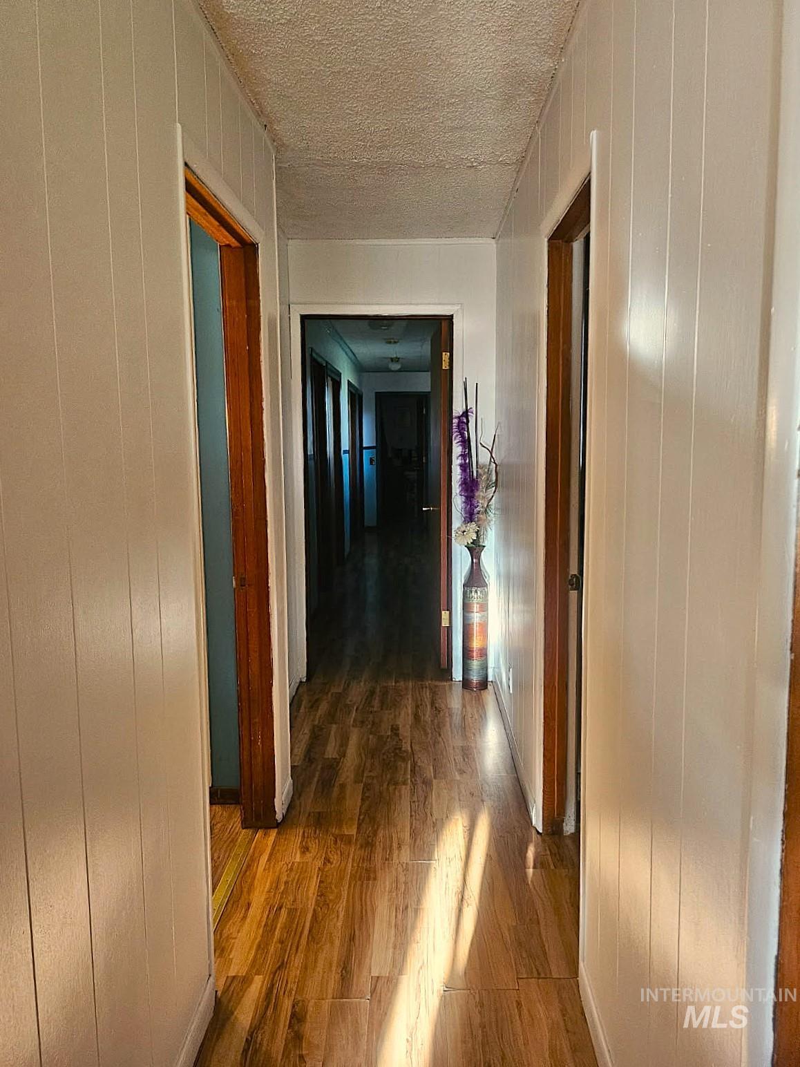 3756 Farrell Road New Meadows, ID 83654 - Photo 19 of 50 Hallway with dark wood-style floors, wooden walls, and a textured ceiling