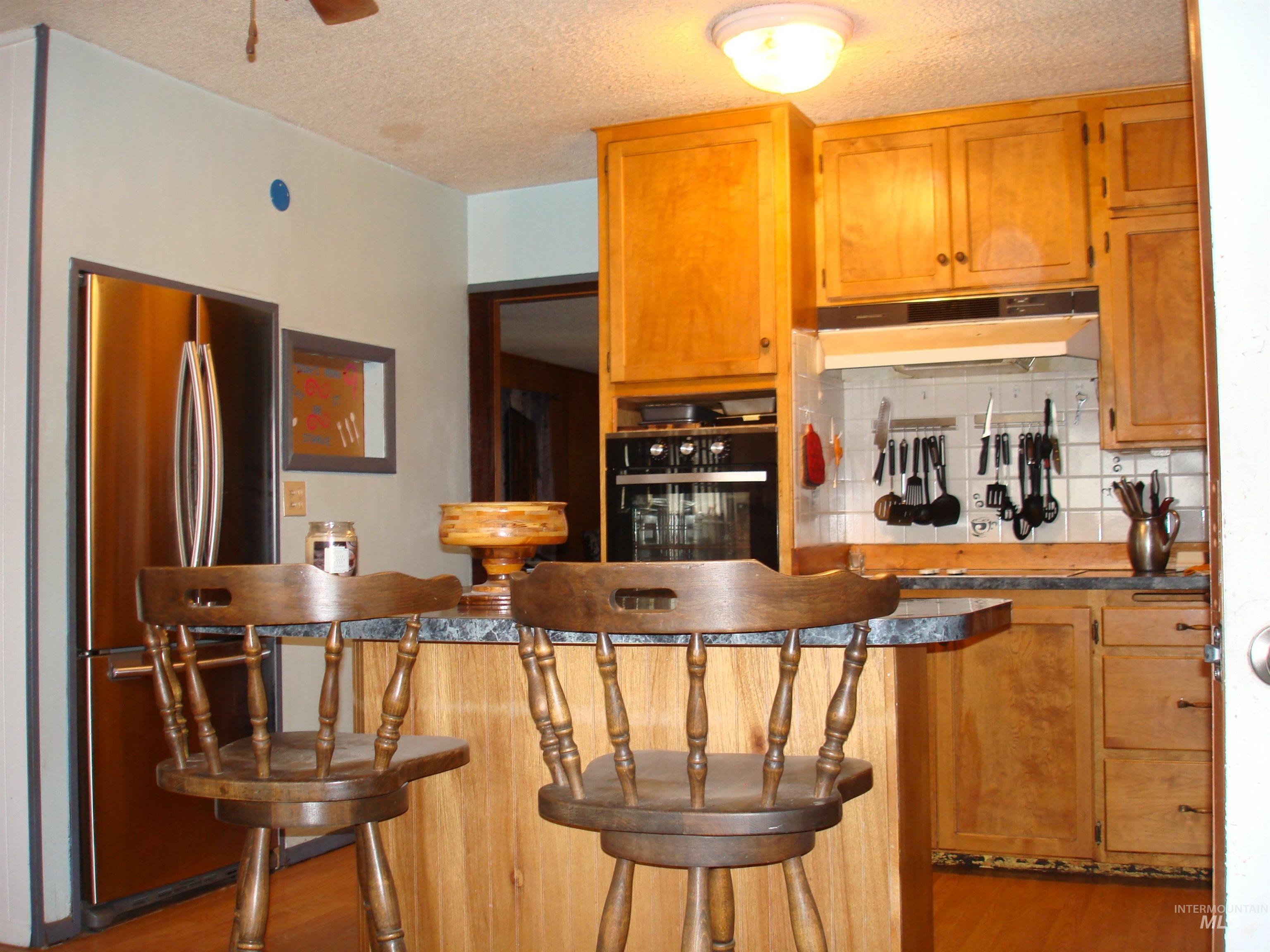 3756 Farrell Road New Meadows, ID 83654 - Photo 9 of 50 Kitchen featuring freestanding refrigerator, dark countertops, tasteful backsplash, black oven, and a textured ceiling