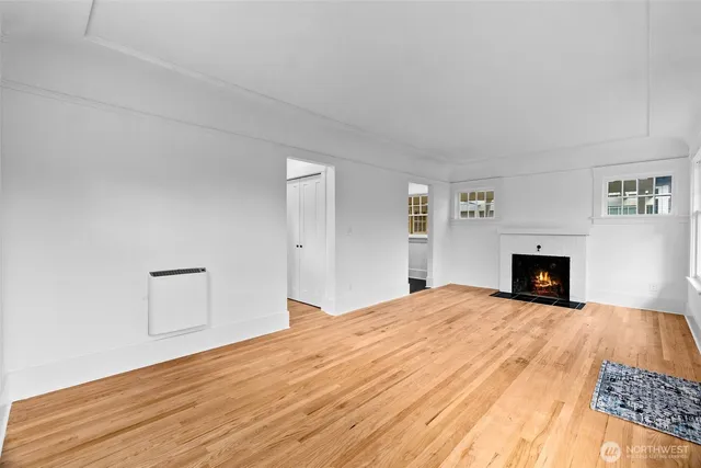a view of empty room with fireplace and wooden floor