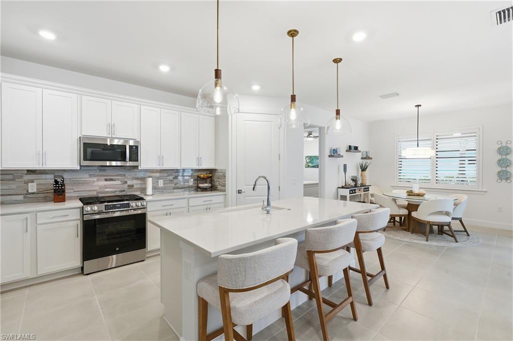 18364 Ridgeline Drive Estero, FL 33928 - Photo 14 of 50 a kitchen with stainless steel appliances kitchen island granite countertop a stove a sink a dining table chairs and view living room
