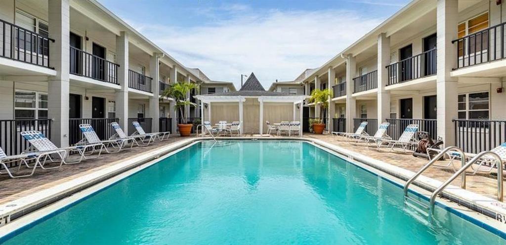 5221 Bayshore Boulevard, Unit 21 Tampa, FL 33611 - Photo 1 of 21 a view of a building with a large pool lawn chairs and couches chair