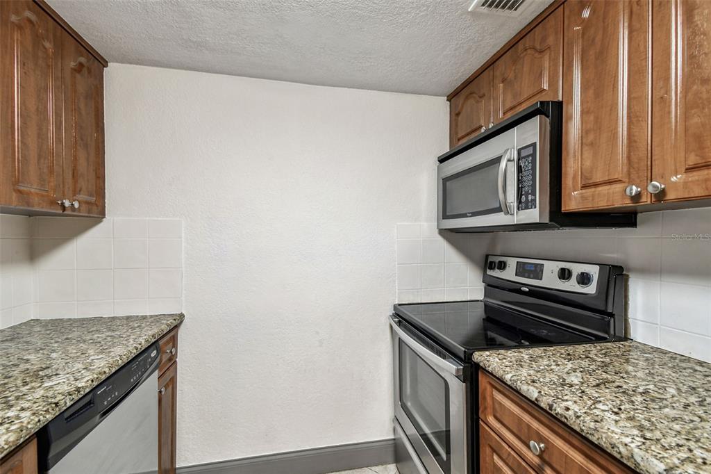 5221 Bayshore Boulevard, Unit 21 Tampa, FL 33611 - Photo 11 of 21 a kitchen with granite countertop cabinets stainless steel appliances and a sink