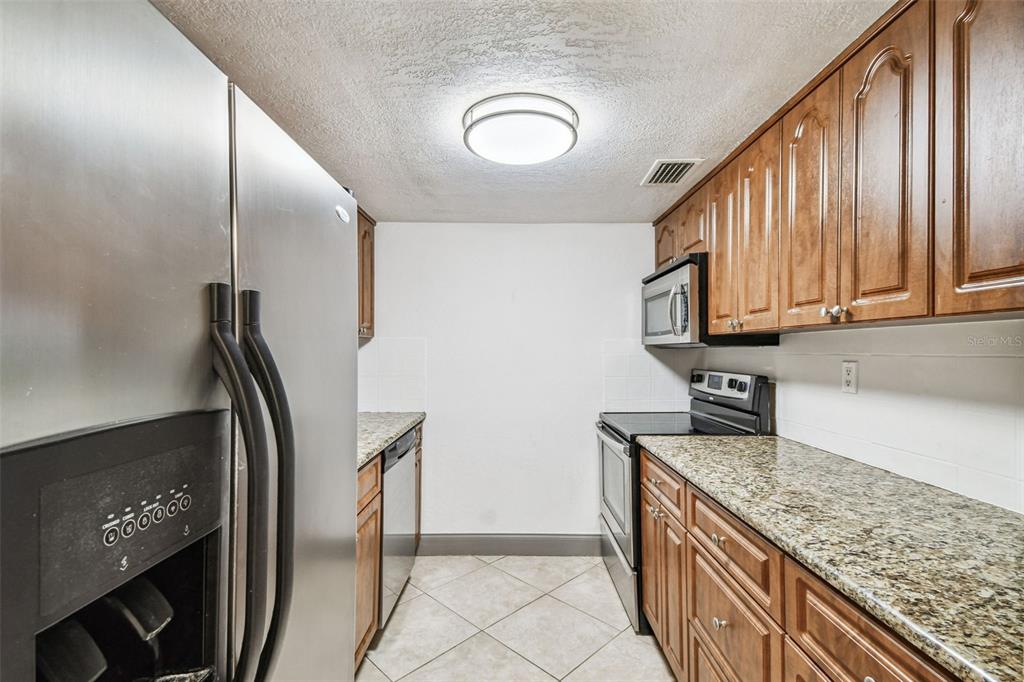 5221 Bayshore Boulevard, Unit 21 Tampa, FL 33611 - Photo 9 of 21 a kitchen with stainless steel appliances granite countertop a refrigerator a stove and a sink
