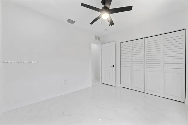an empty room with windows and ceiling fan