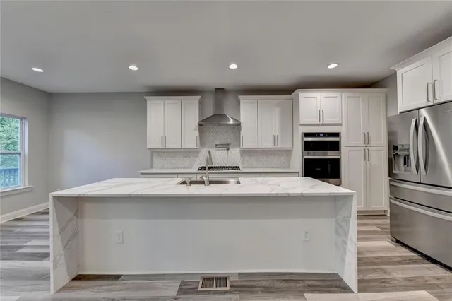 a kitchen with stainless steel appliances a stove top oven a refrigerator and white cabinets