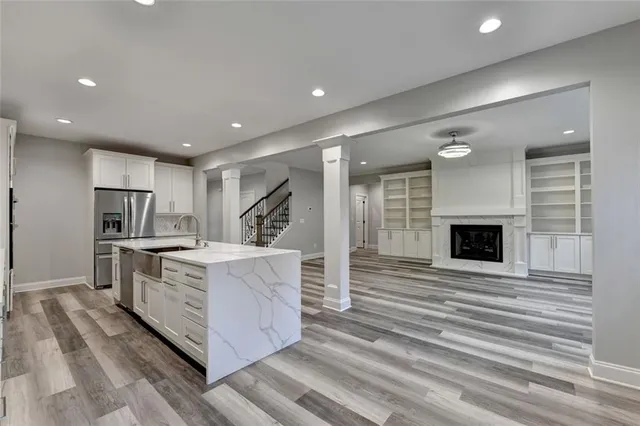 an empty room with wooden floor chandelier fan and windows