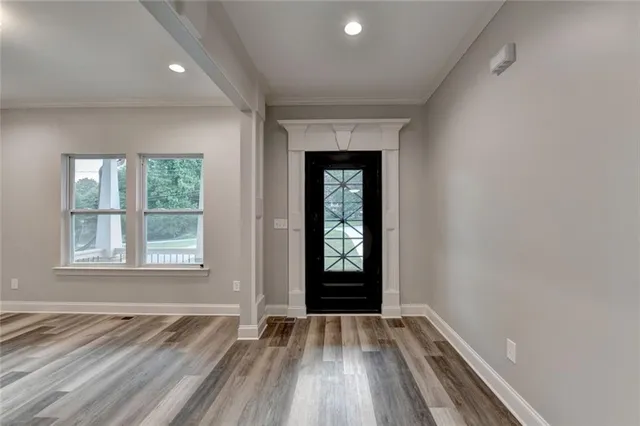 an empty room with wooden floor and windows