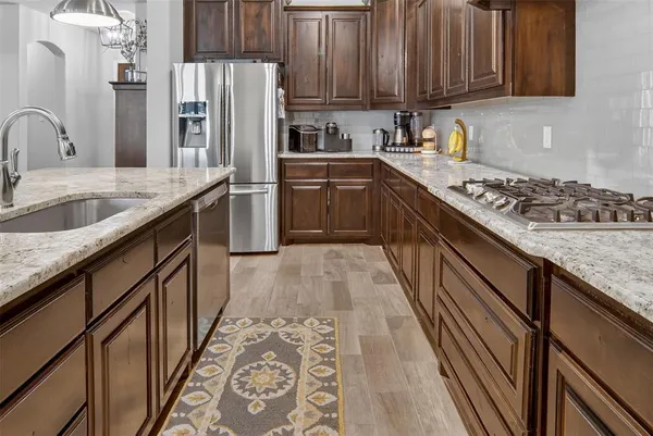 a kitchen with granite countertop a sink a counter top space stainless steel appliances and cabinets