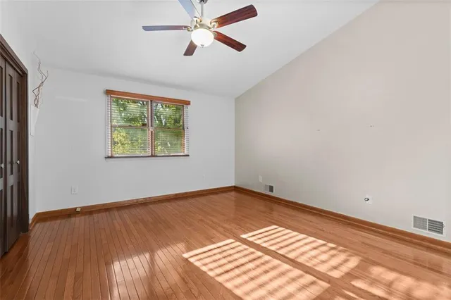 a view of empty room with wooden floor and fan