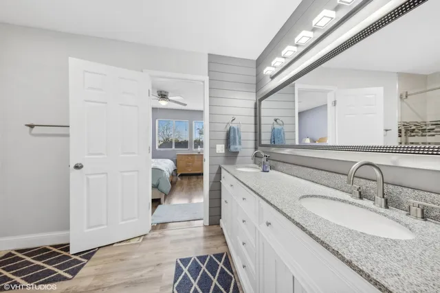 a bathroom with a granite countertop double vanity sink and a mirror