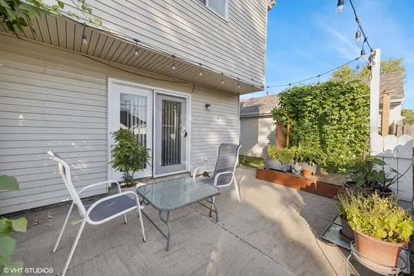 a patio with table and chairs and potted plants