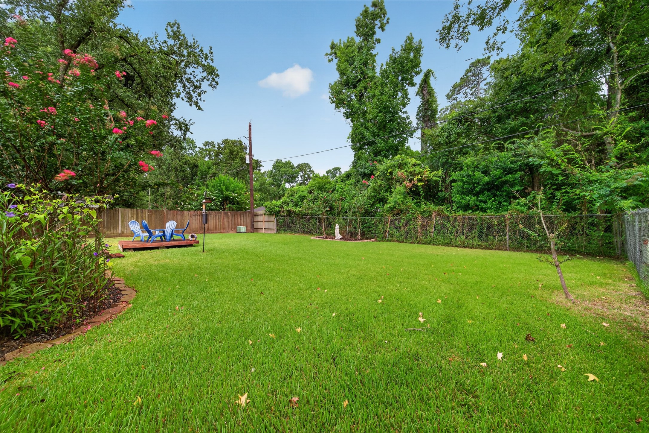 24719 Wilderness Road Spring, TX 77380 - Photo 42 of 42 Spacious backyard featuring a well-maintained lawn, a wooden deck with seating, and a privacy fence. Ideal for outdoor activities and relaxation.