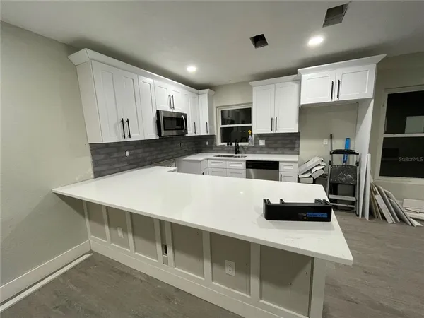 a kitchen with kitchen island white cabinets and refrigerator