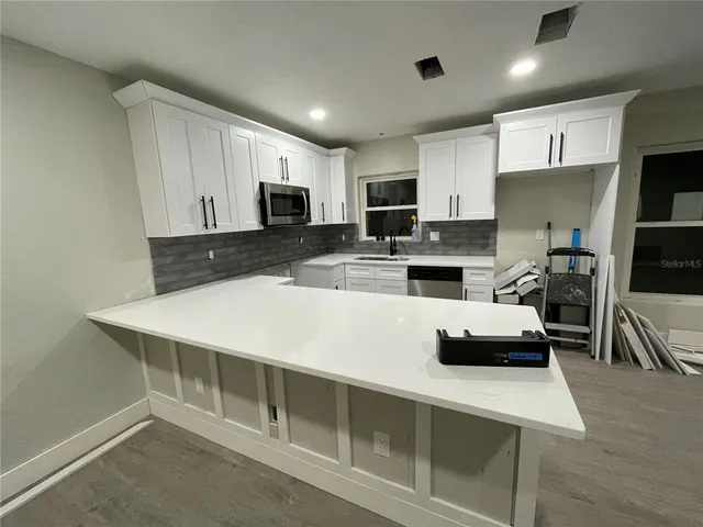 a kitchen with kitchen island white cabinets and refrigerator