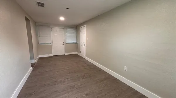 a view of a big room with wooden floor and windows