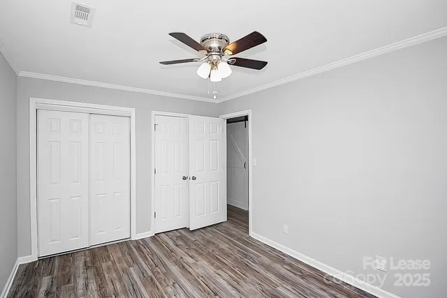 a view of an empty room with wooden floor and a ceiling fan