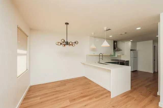 a kitchen with stainless steel appliances granite countertop a sink a stove a refrigerator and a window