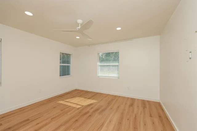 a view of empty room with wooden floor and fan
