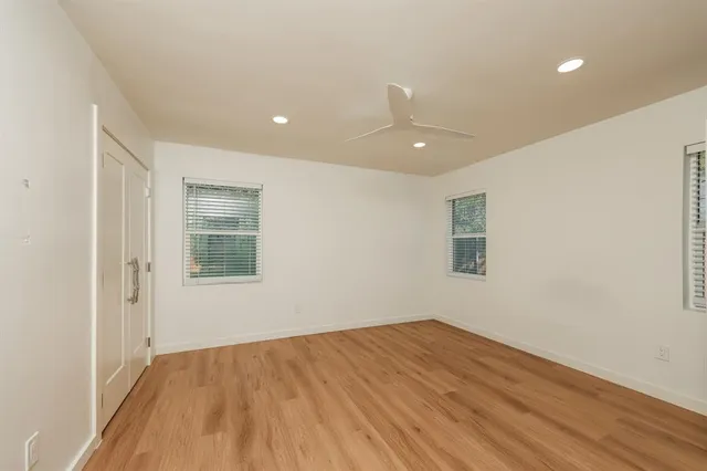 a view of empty room with wooden floor and fan