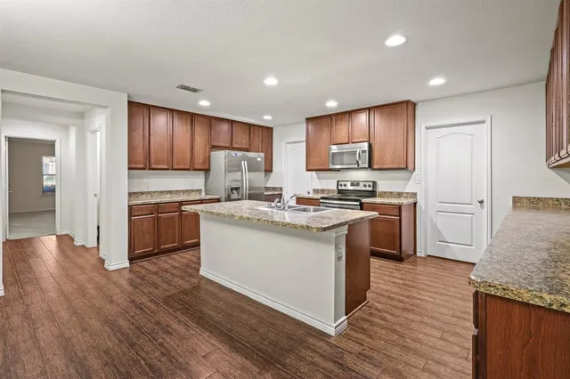 a kitchen with granite countertop a sink cabinets and stainless steel appliances