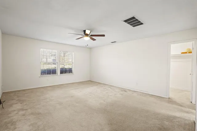 an empty room with windows and ceiling fan