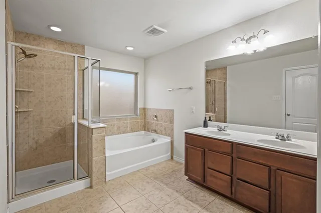 a spacious bathroom with a tub sink shower and mirror