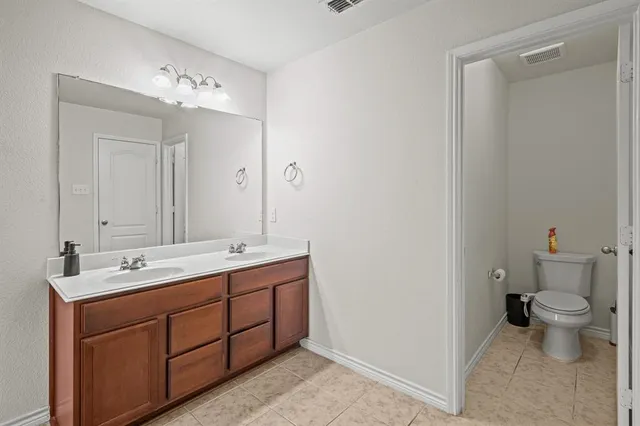 a spacious bathroom with a double vanity sink toilet and a mirror
